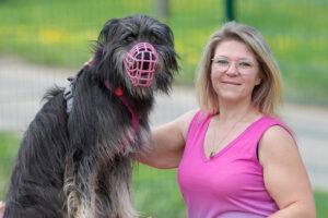 Hund mit Maulkorb und Trainerin