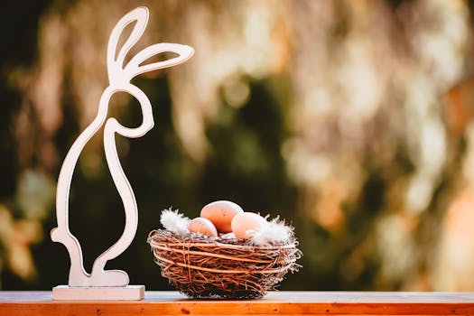 Artistic photo of a wooden bunny decoration beside a nest with eggs, set against a blurred outdoor backdrop.